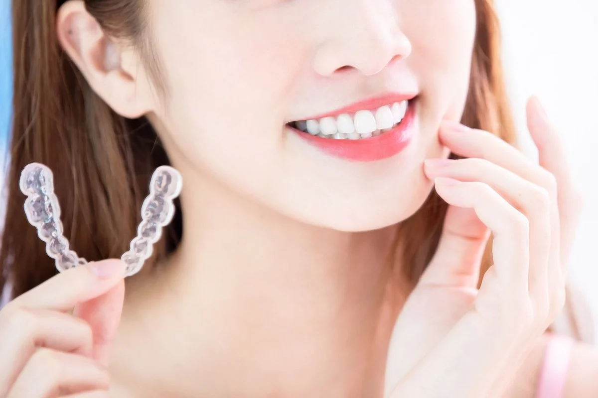 A smilling women holding invisalign